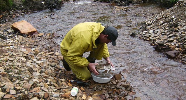 Man collecting sediment in a stream bed