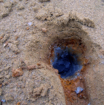 A hole in the tailings pile showing antimony