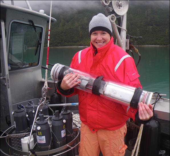 researcher in orange coat holds device