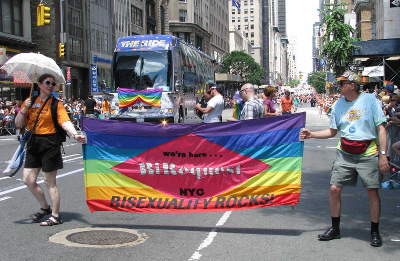 A march down a street with two people holding a rainbow banner