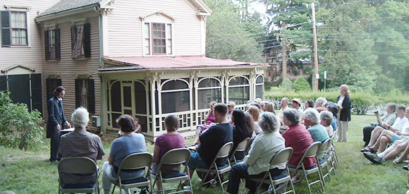 group of people gathering in the lawn of an historic house to learn about fire prevention