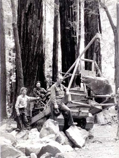 Black and white image of people posing with boulders alongside towering coast redwood trees