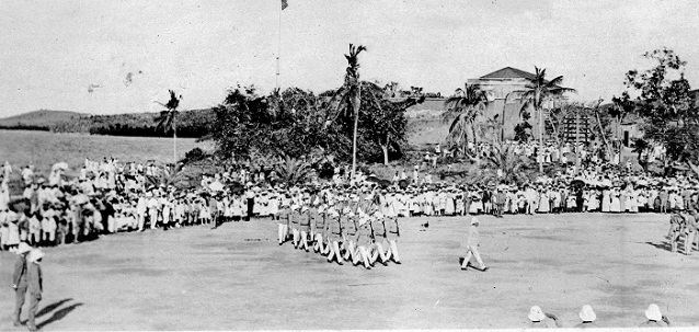 Historical black and white image of troops marching on a parade field