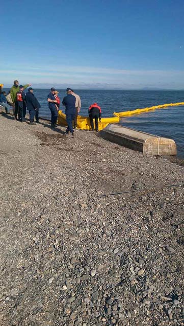 people standing on a rocky beach, putting a yellow boom out into the water