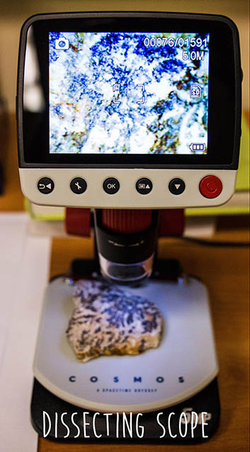 a microscope with a screen showing a close up of a rock with black streaks in it