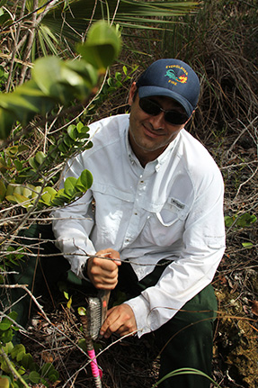 A man scrapes a steel brush against a rusty stake.