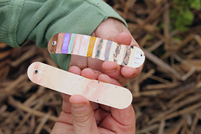 Close-up of hands holding metal tags with heat-sensitive paint.