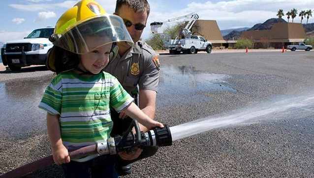 young boy holds a fire hose for the first time. 