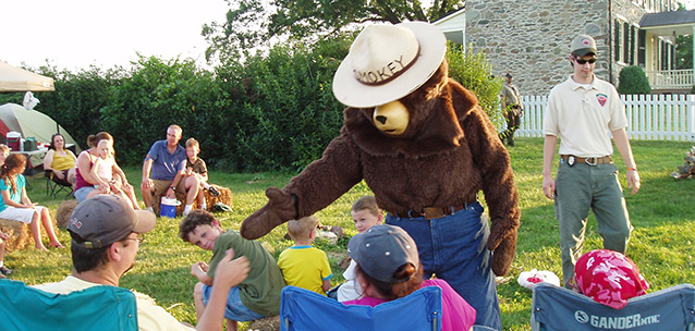 smokey bear shaking hands with the public at a backyard BBQ