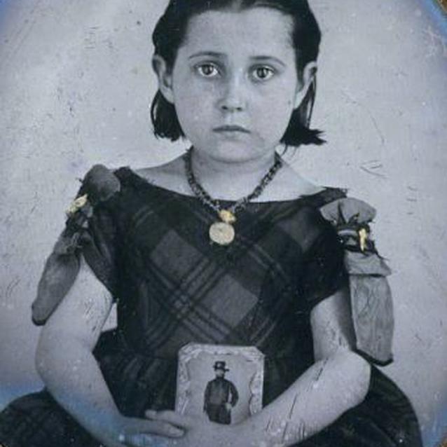 Photo of a young girl in mourning dress with a photograph of her cavalryman father