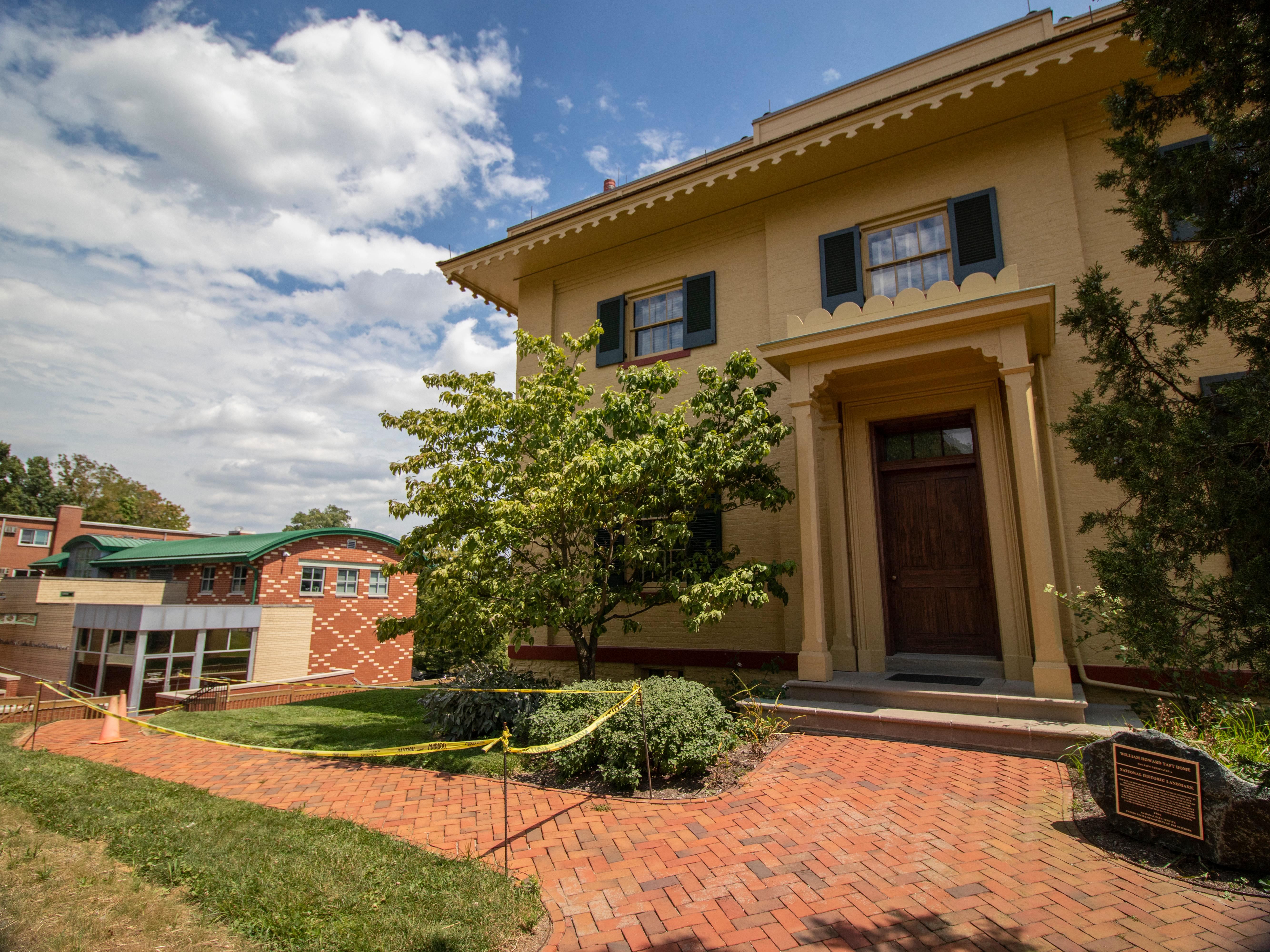 A yellow building to the right with a red brick sidewalk leading to a tan and red building