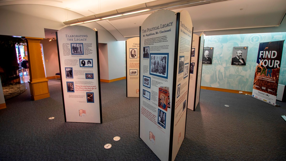 Tall display columns arranged in rows inside of a large room with photos and text on them.
