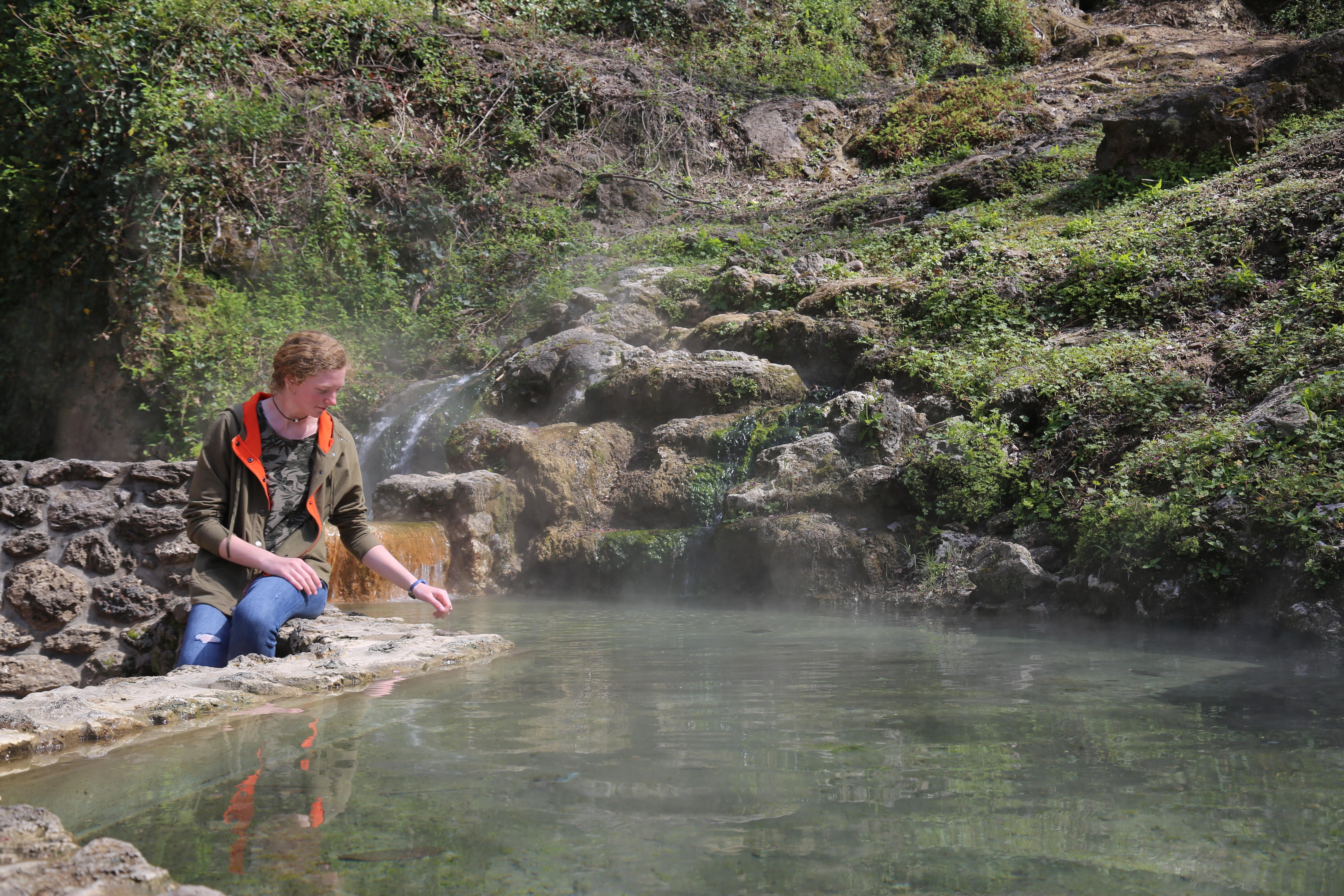 women sitting on the stone wall at the hot water cascade as the vapor rises