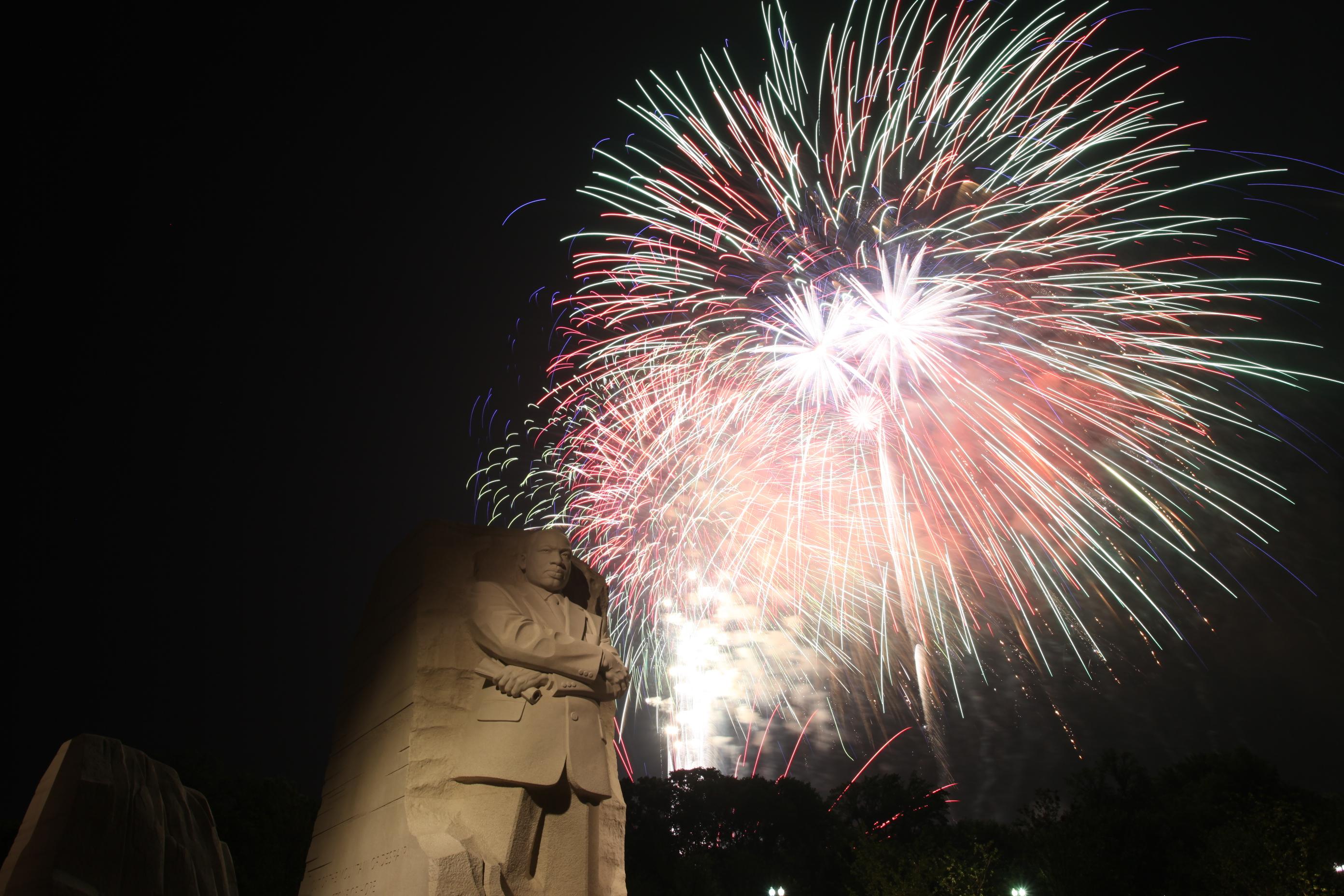 Look upward, fireworks burst behind the stone sculpture of Martin Luther King, Jr.