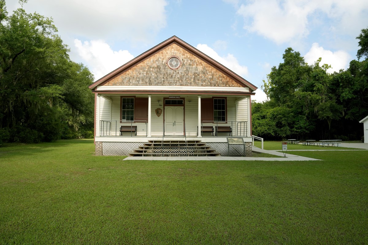 A large white wooden building with red trim and a porch.