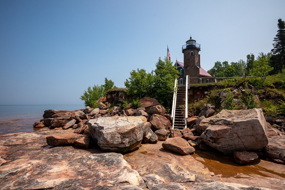 Photograph of rocky shoreline and steps leading to historic lighthouse. 