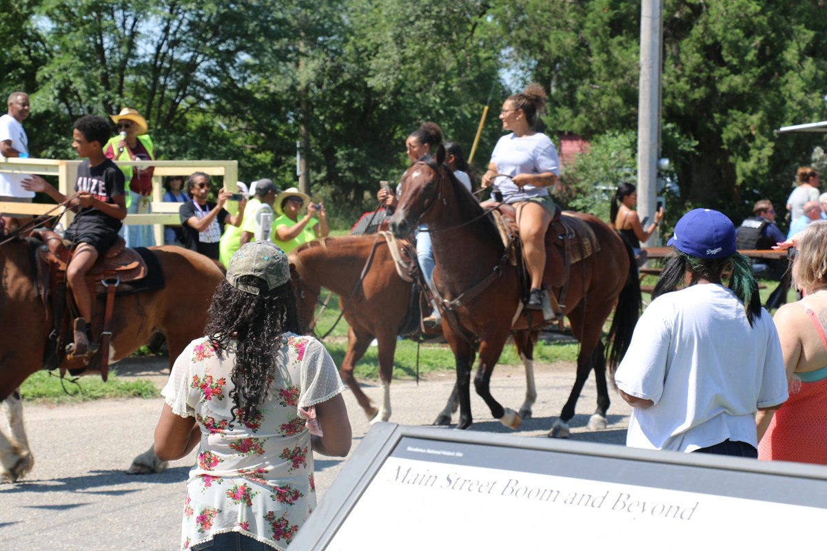 A group of people watching people on horseback during a parade