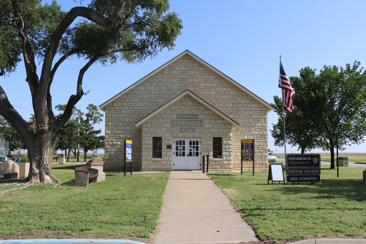 A limestone brick building with grass and trees around it