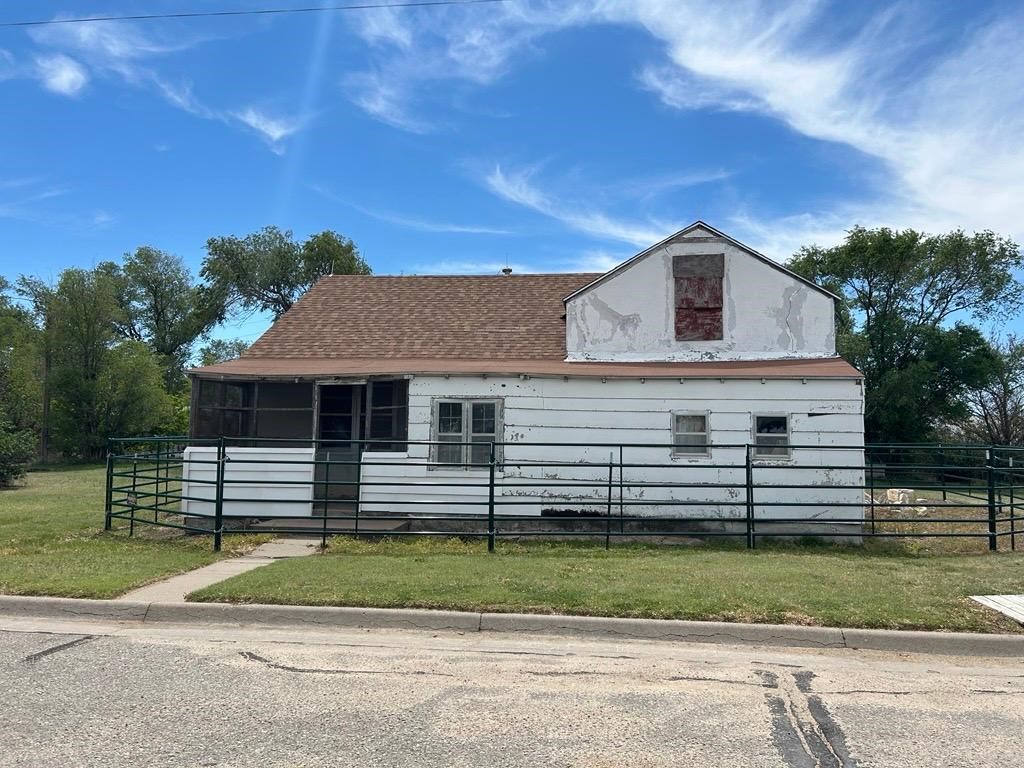 A white building with a green metal bar fence around it