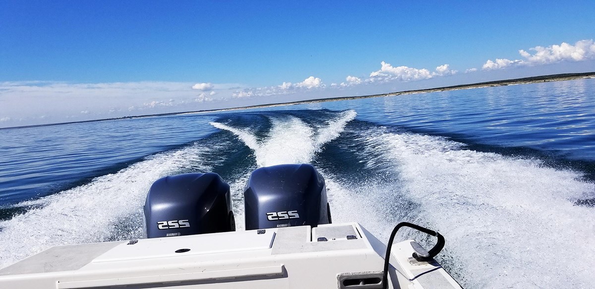 Looking out the stern of a dual engine motorboat banking starboard with large wakes following.