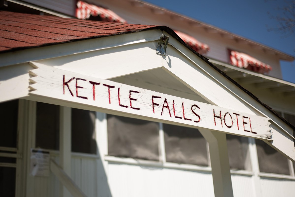Photograph of rustic wooden sign on building front with "Kettle Falls Hotel" painted in red.