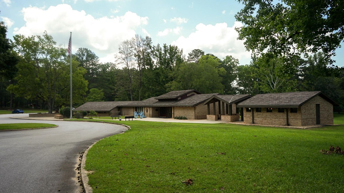 Image displays a lightly colored brick building surrounded by freshly mowed grass.