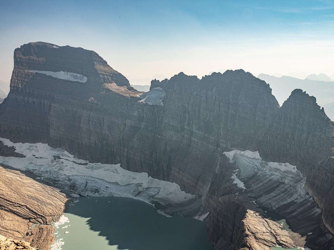 a mountain glacier with a lake and mountains behind