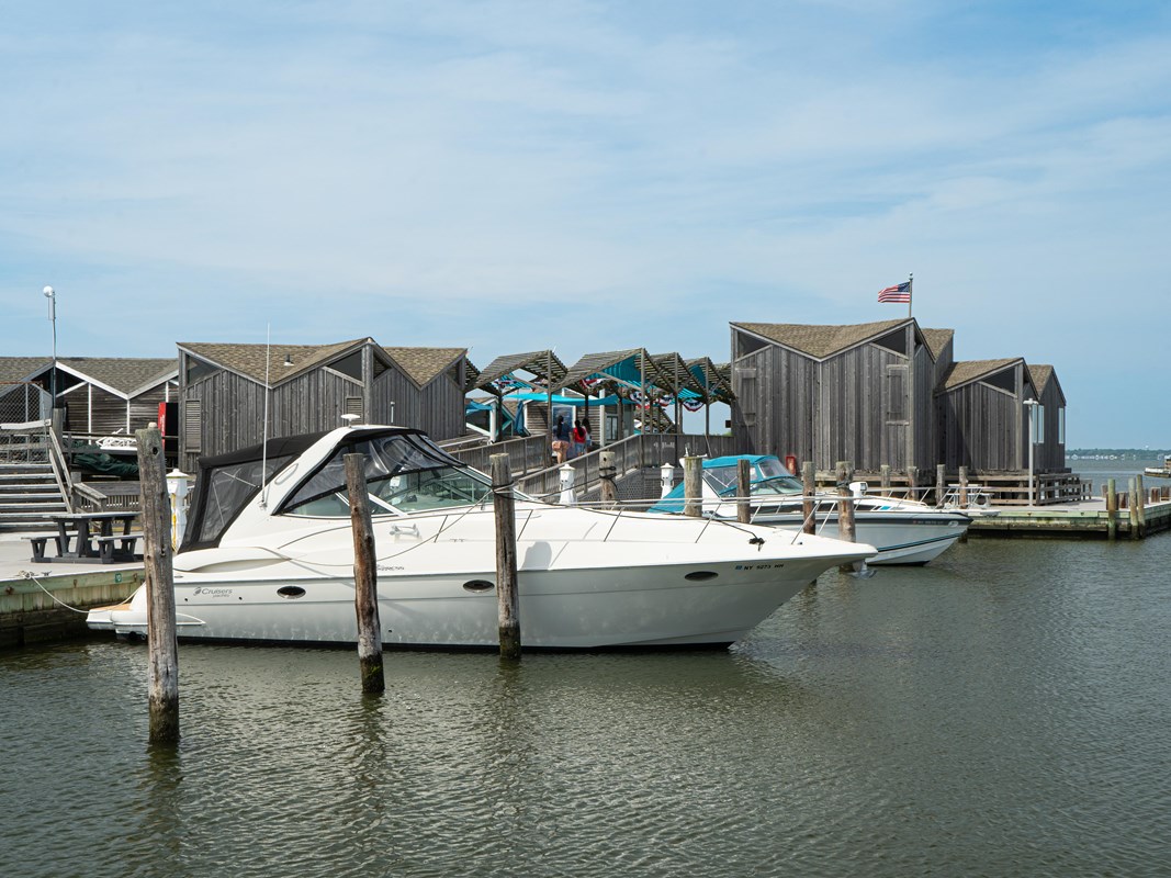 Boats docked in a marina with wood-sided buildings surrounding.