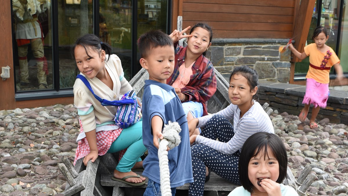 Multiple children sit in a boat, smiling at the camera. 