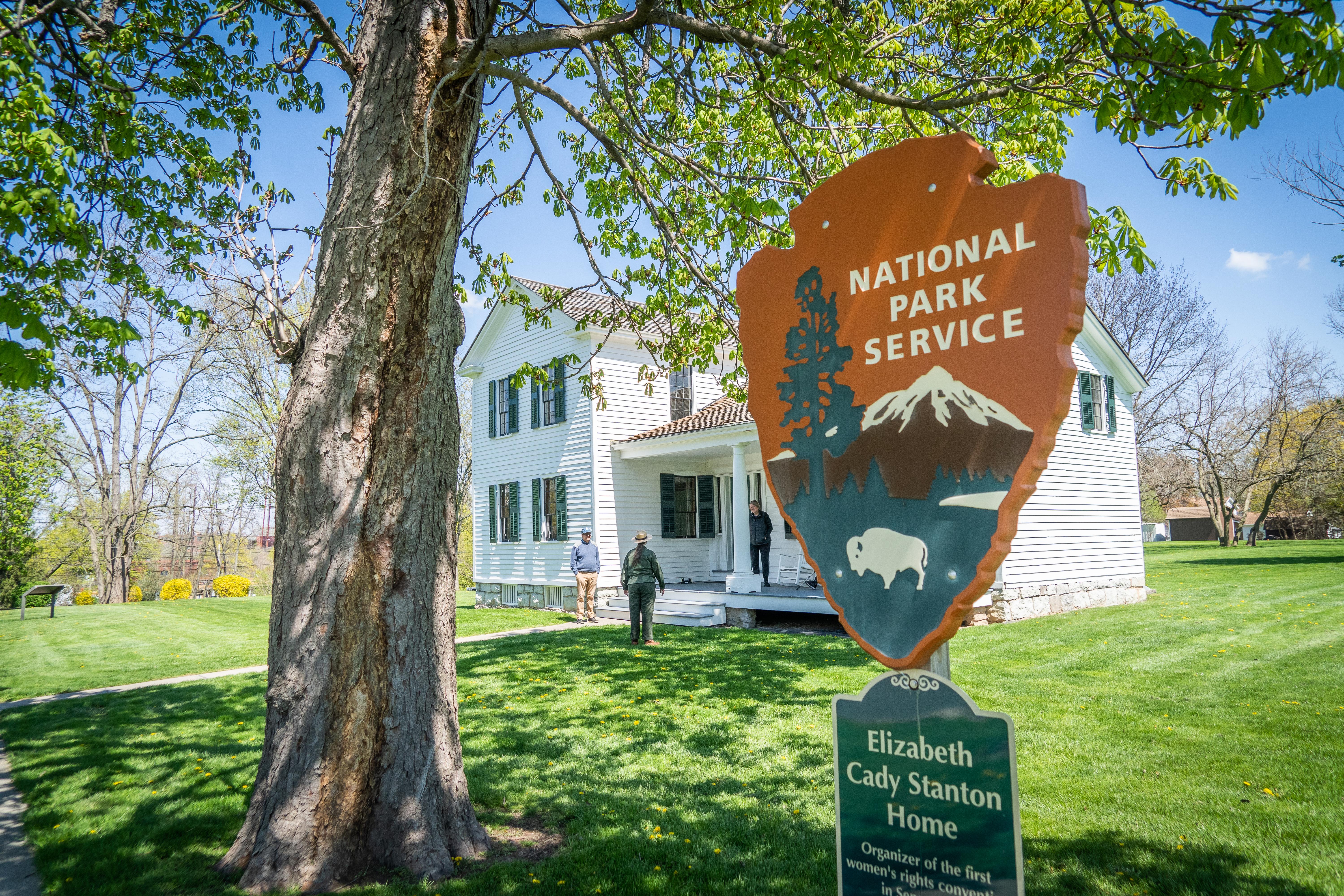 The Elizabeth Cady Stanton House with a tree and National Park Service sign in the front yard