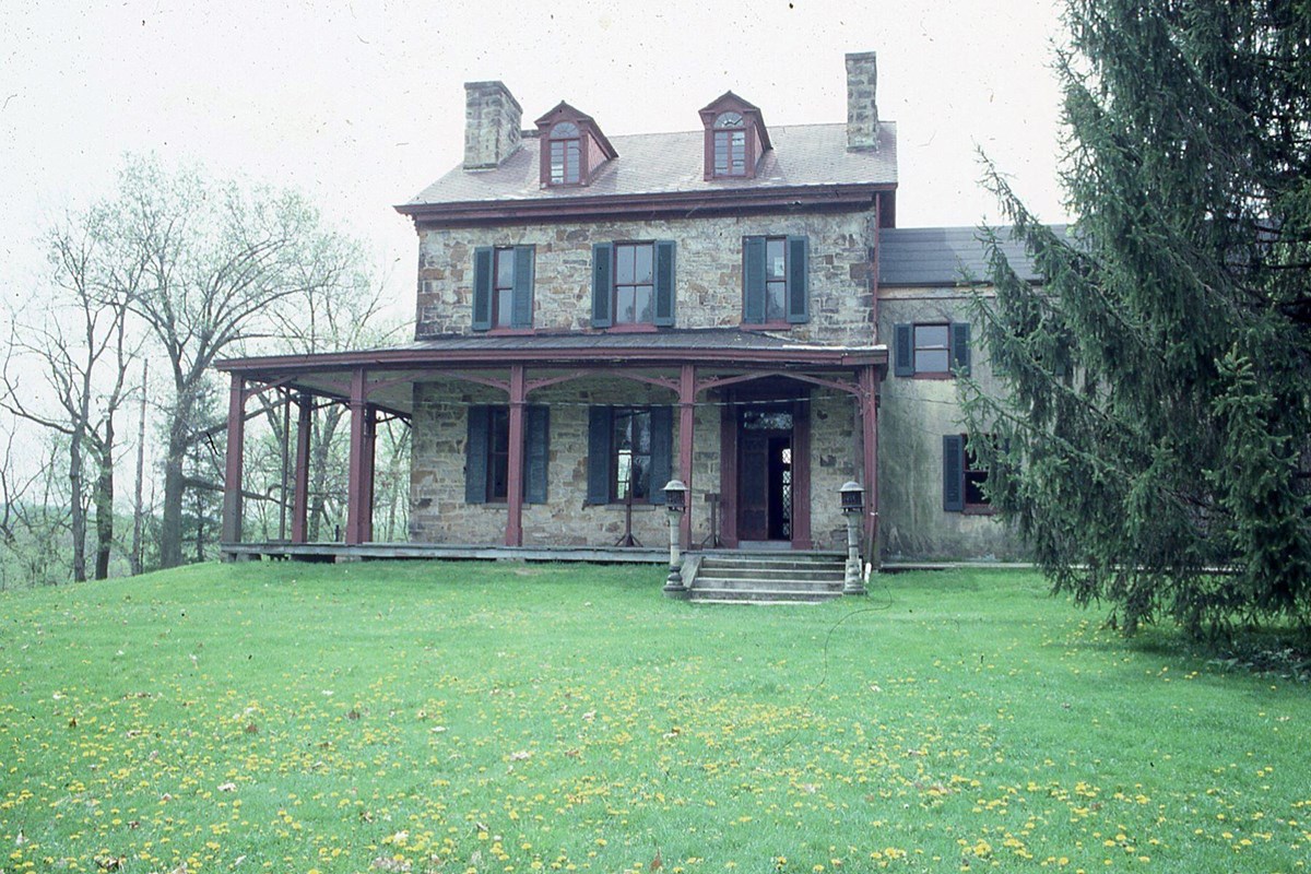 spring green lawn and trees surrounding old stone house