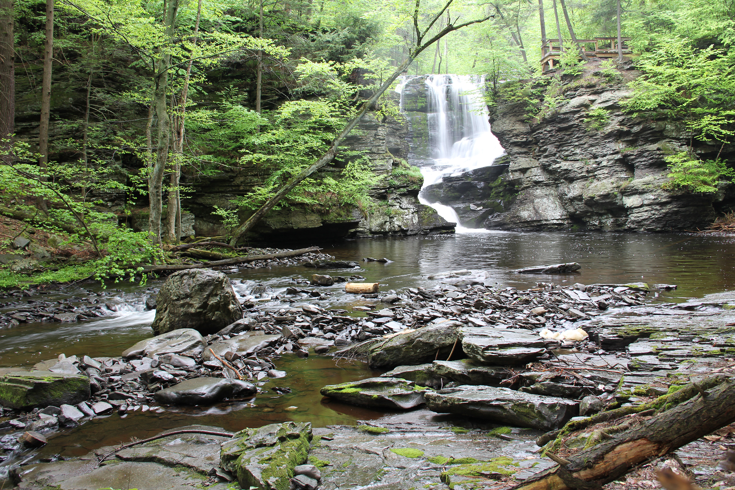 A waterfall flows toward the viewer along a rocky riverbed.