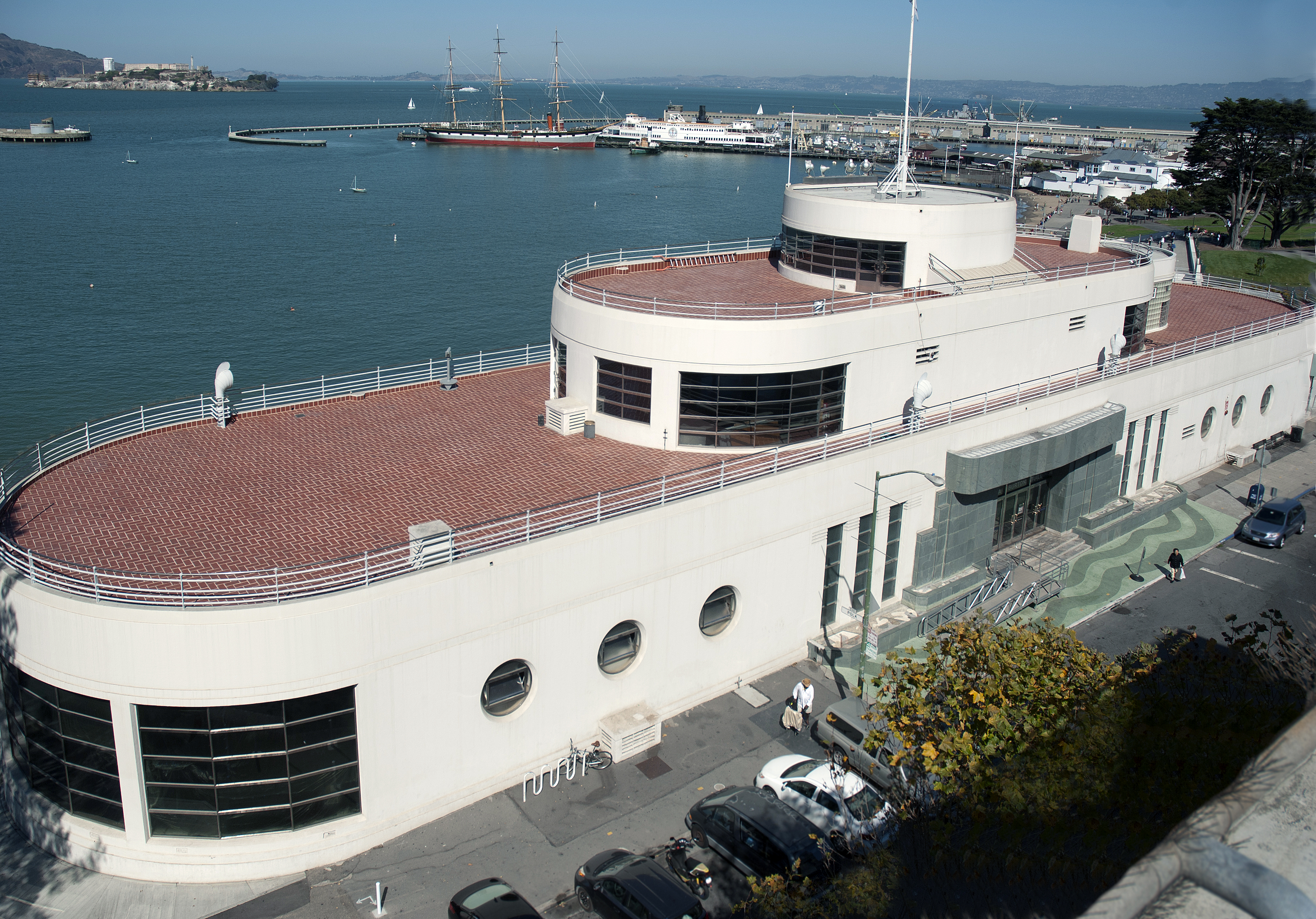 A red-roofed building with water and a pier behind it.