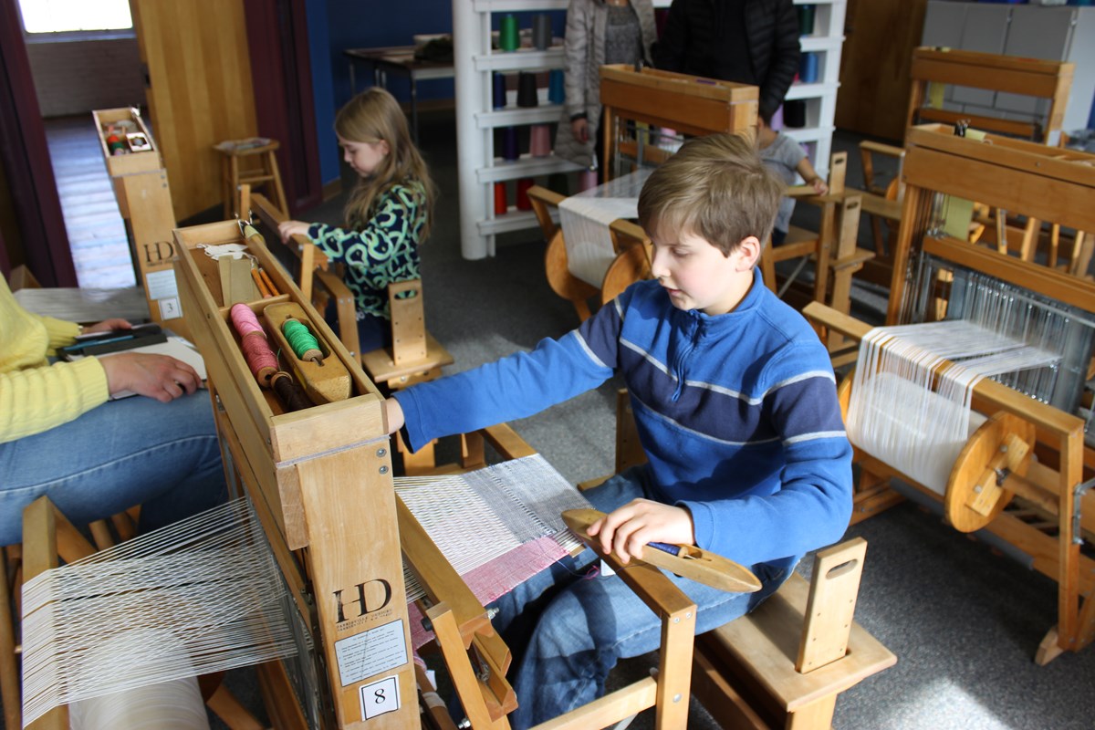 Two students weaving on the looms at the education center. 
