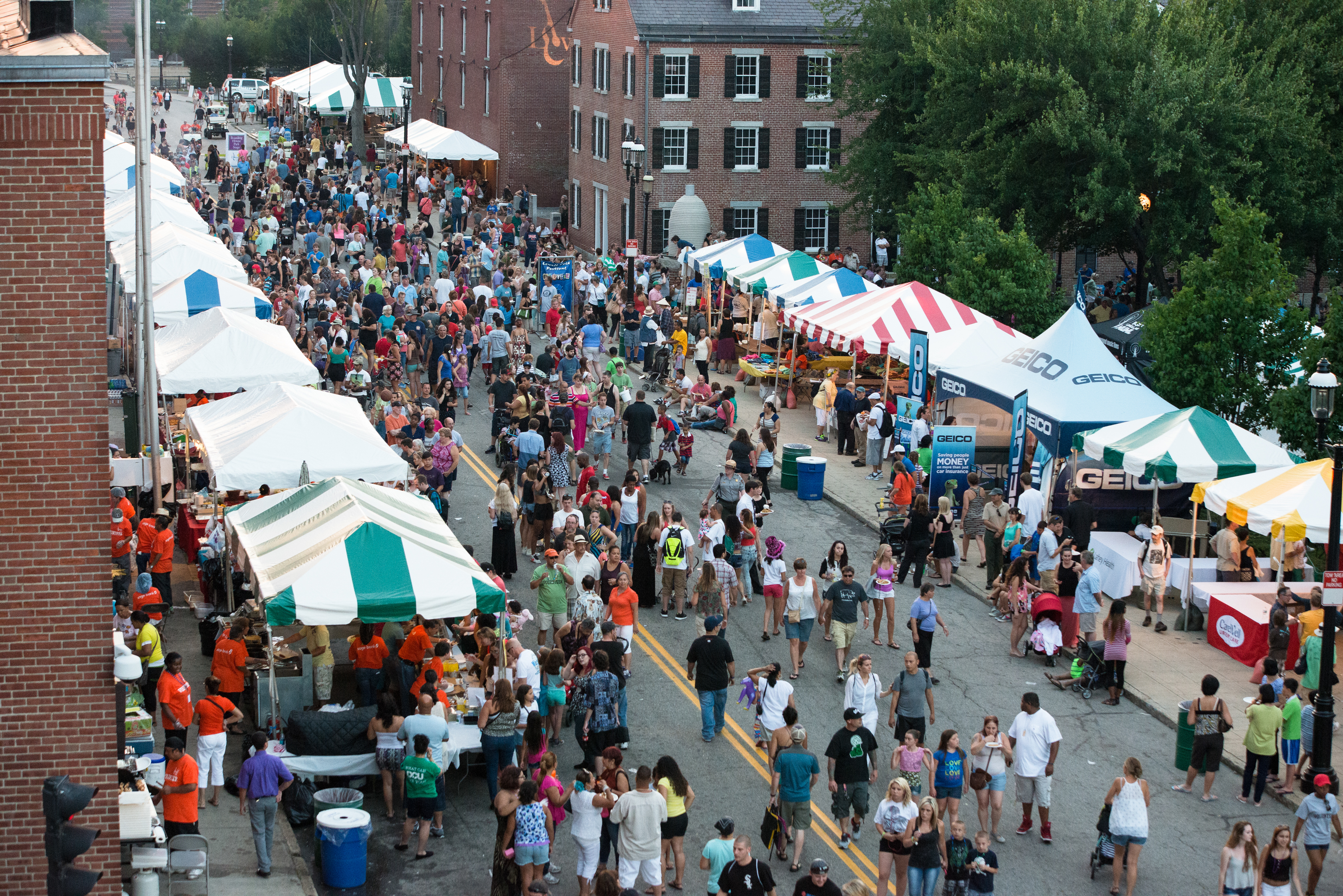 Street scene with lots of tents and crowds listening to Folk Festival music at Boardinghouse Park.