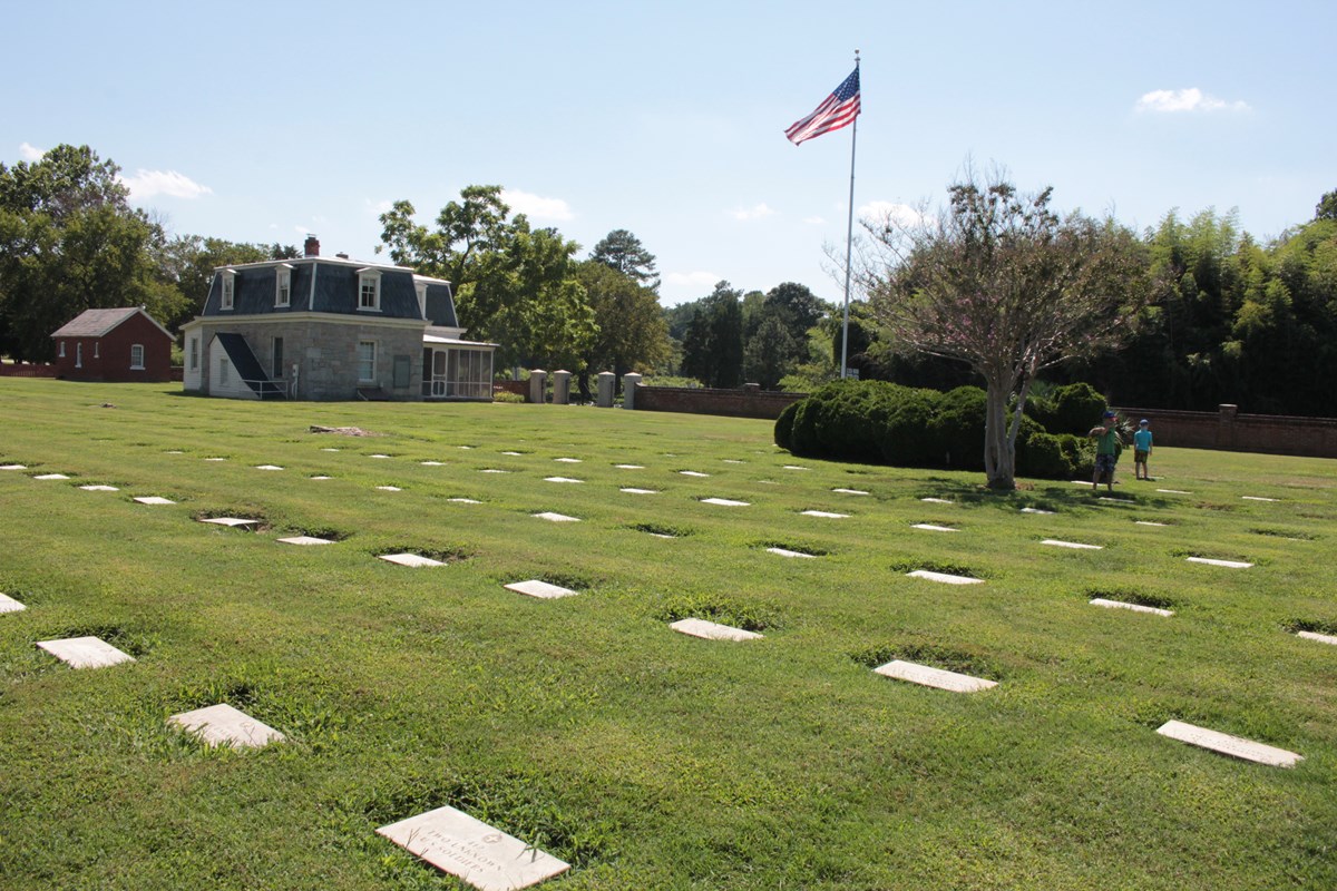 National Cemetery showing tombstones, American Flag and Cemetery Lodge in sunlight.  