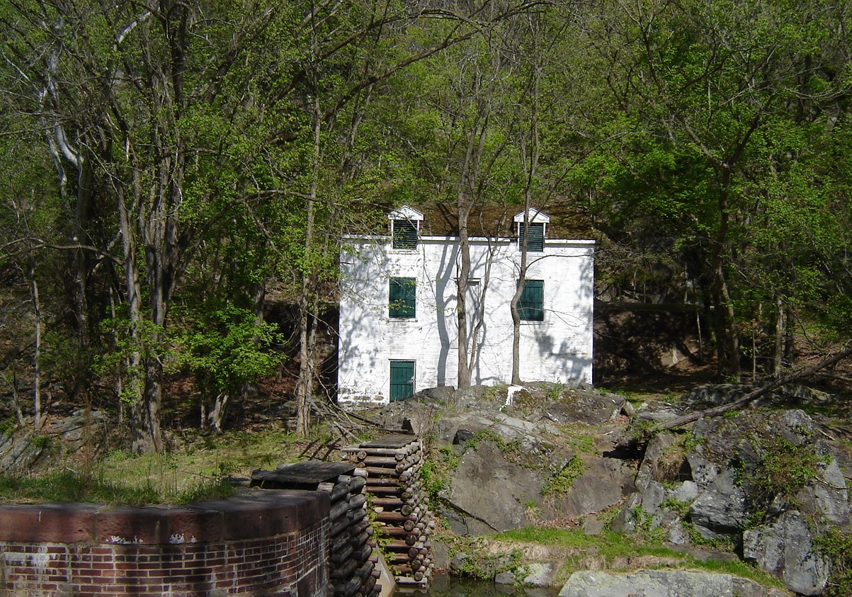 A whitewashed lockhouse sits above a stone lock with wooden crib.