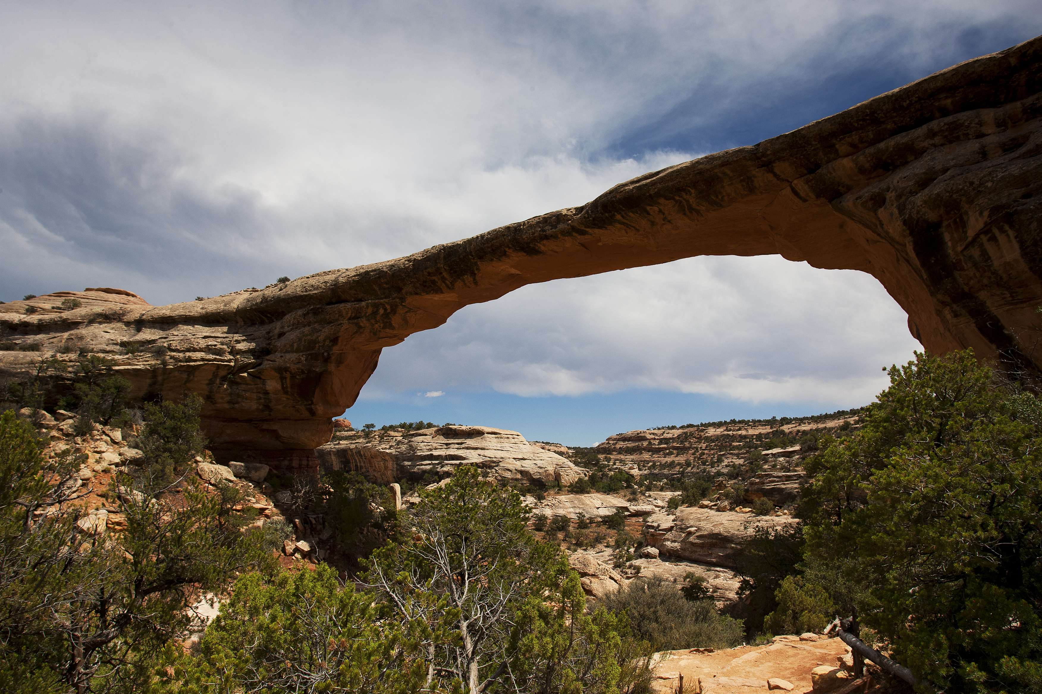 Sipapu Bridge with a blue sky and clouds overhead