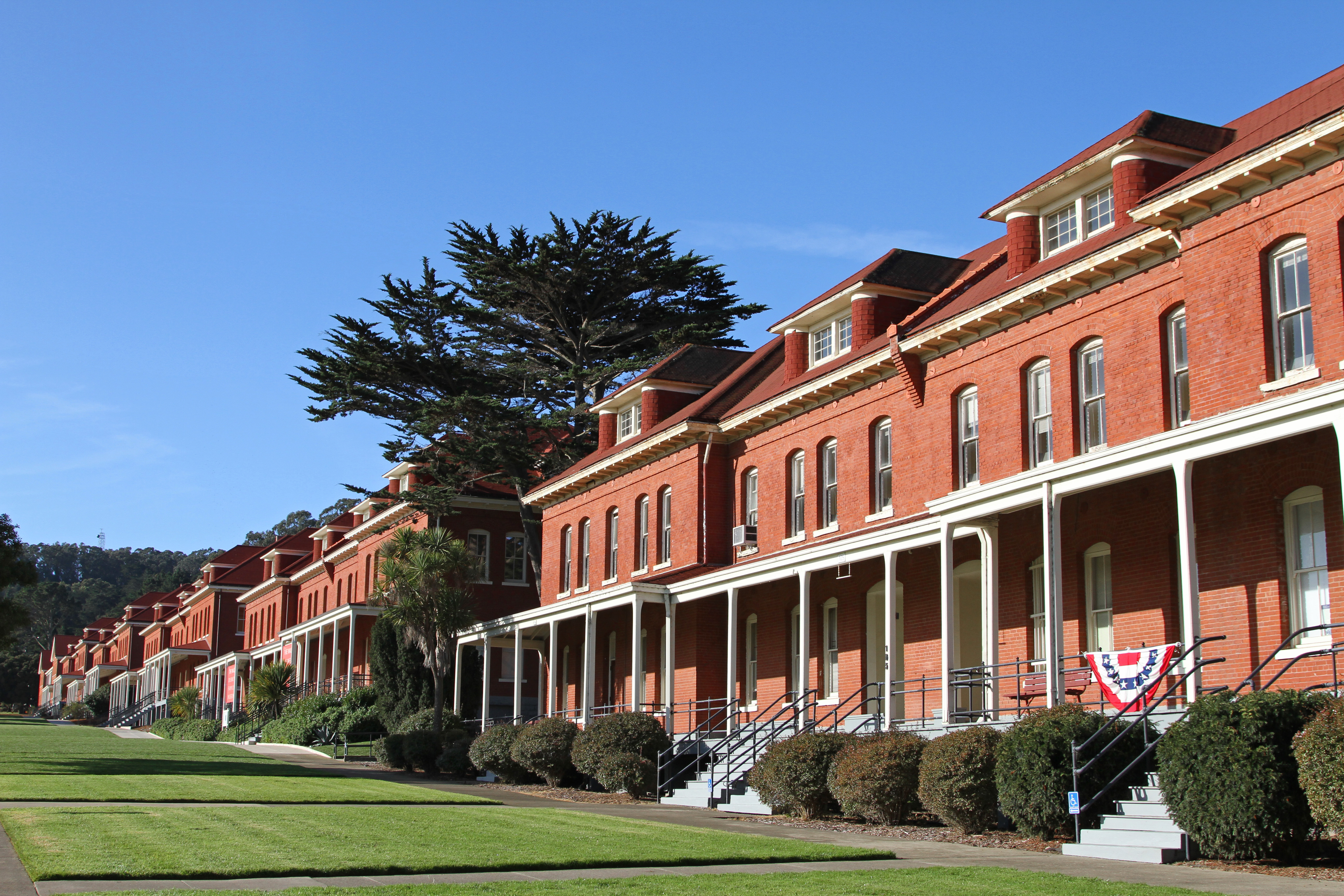 A long row of red brick barracks with green lawns in front extends into the distance.