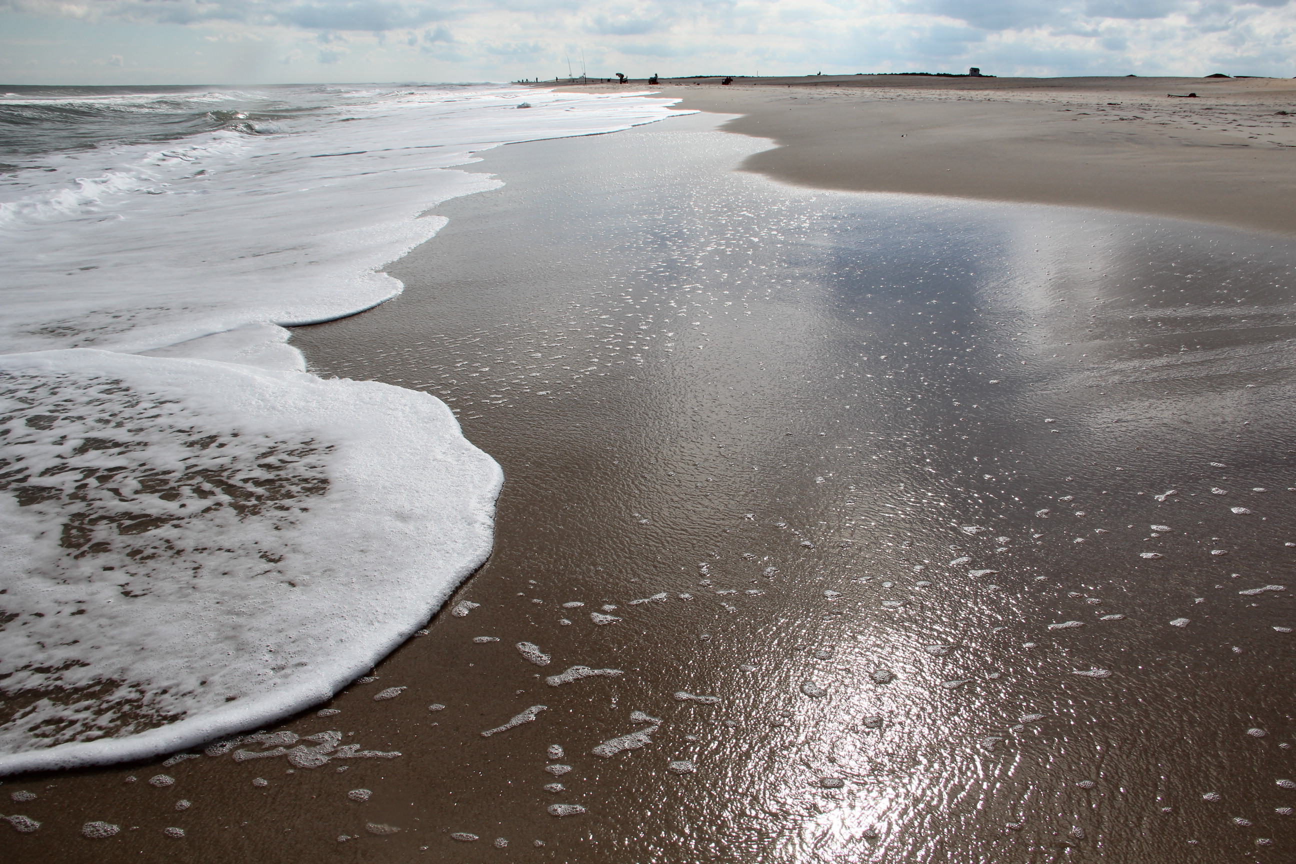 waves on Assateague beach with people fishing in the background