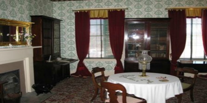 room with tall windows and fireplace, round table containing lamp and surrounded by chairs