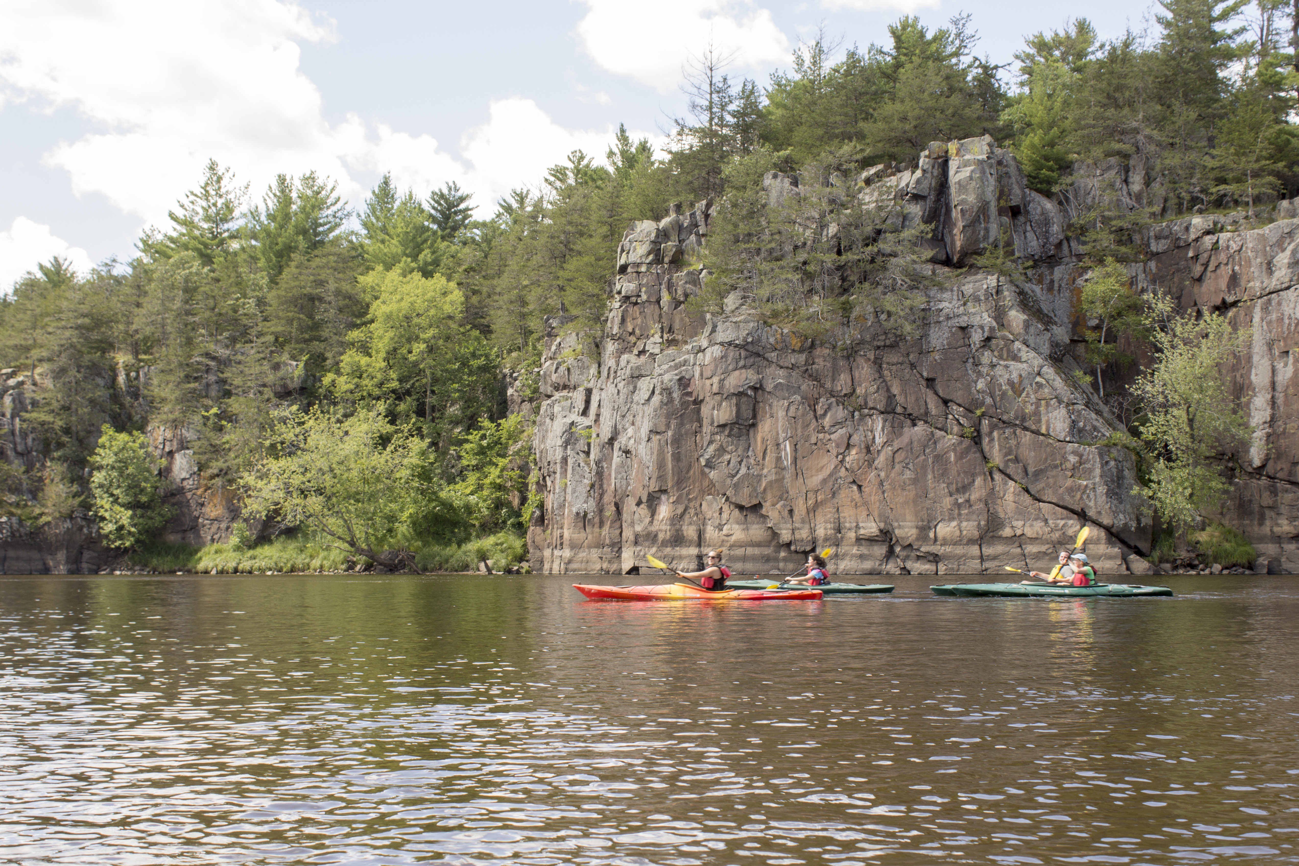 Kayakers pass impressive cliffs.