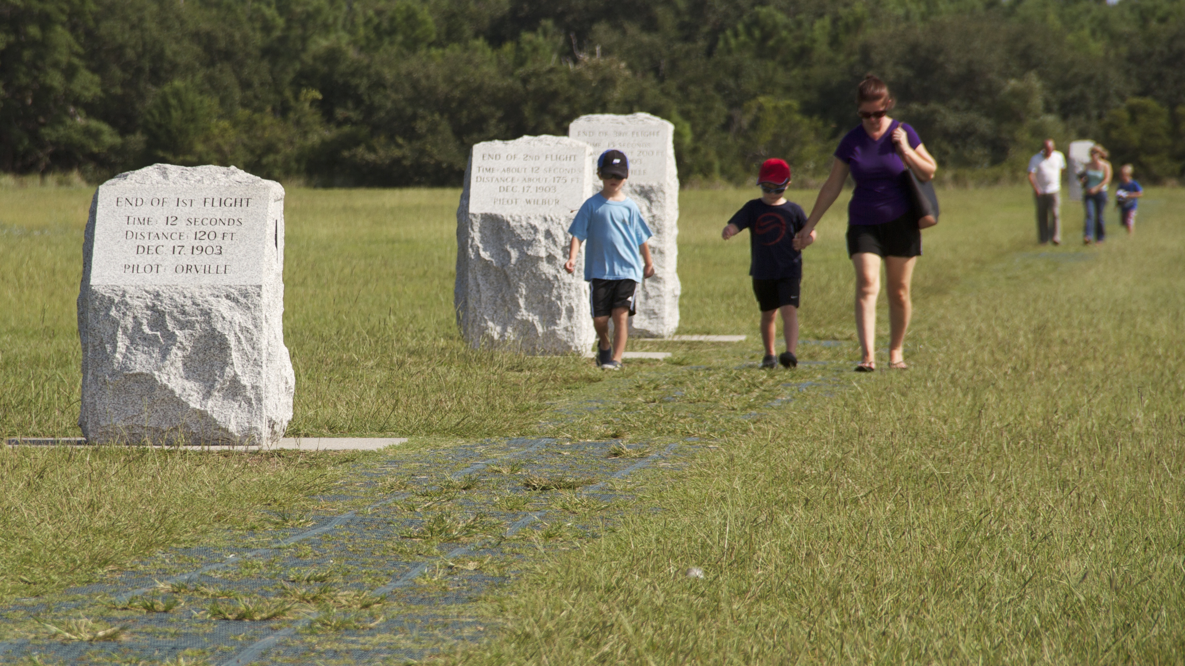 Visitors walk along the flight line where Wilbur and Orville Wright flew and landed.