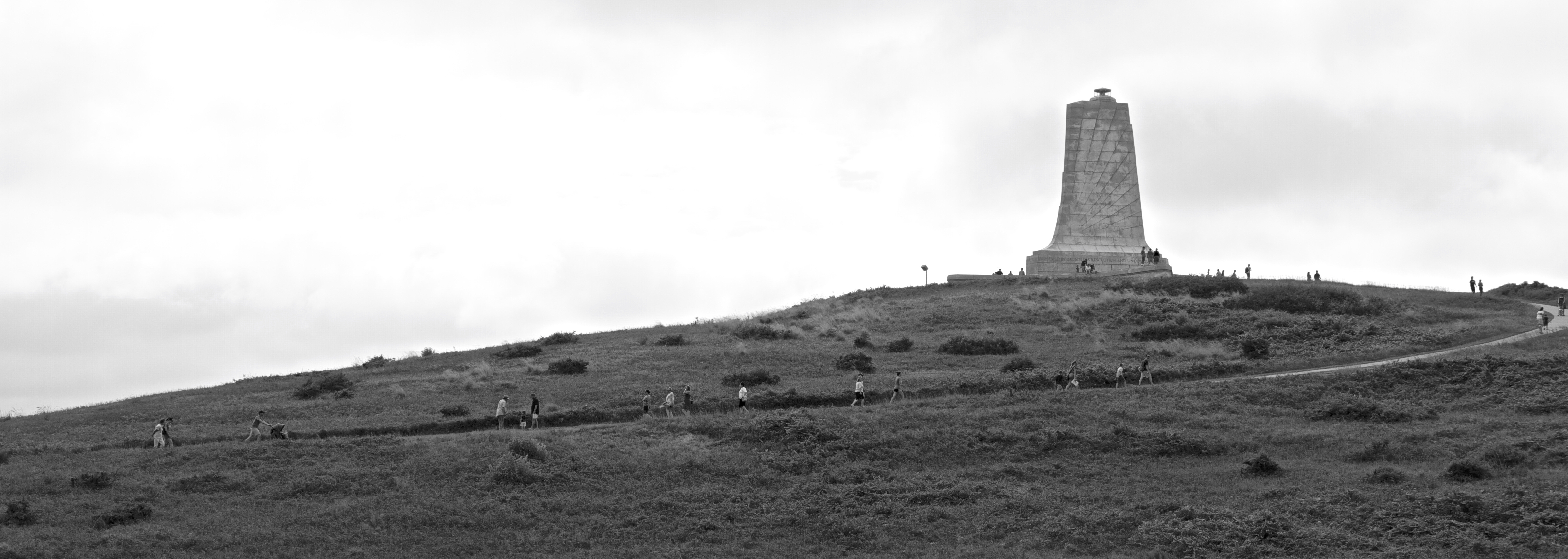 Visitors moving along a sidewalk to the top of the hill where the monument stands.