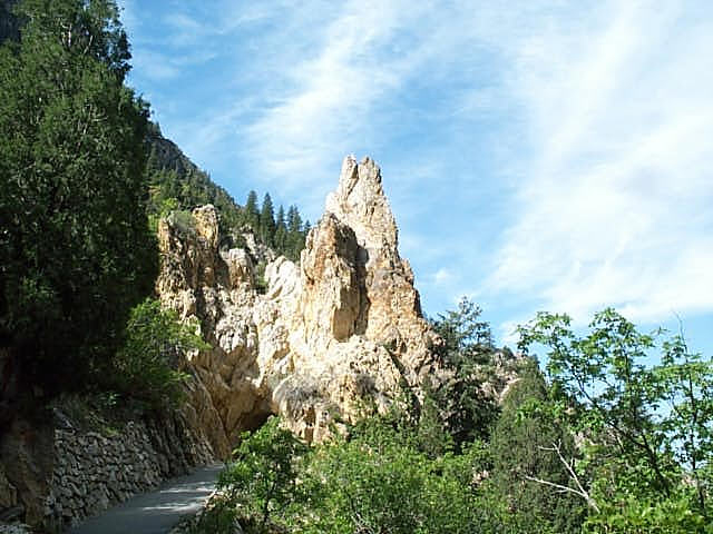 White-orange quartzite surrounded by greenery stands against a blue sky