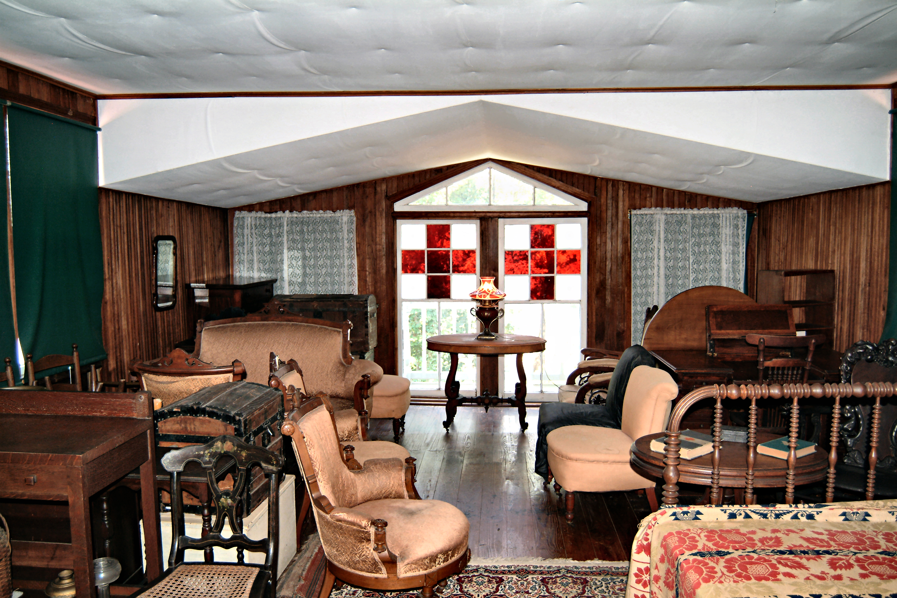 Red Cross stained glass windows in room with stored furniture.