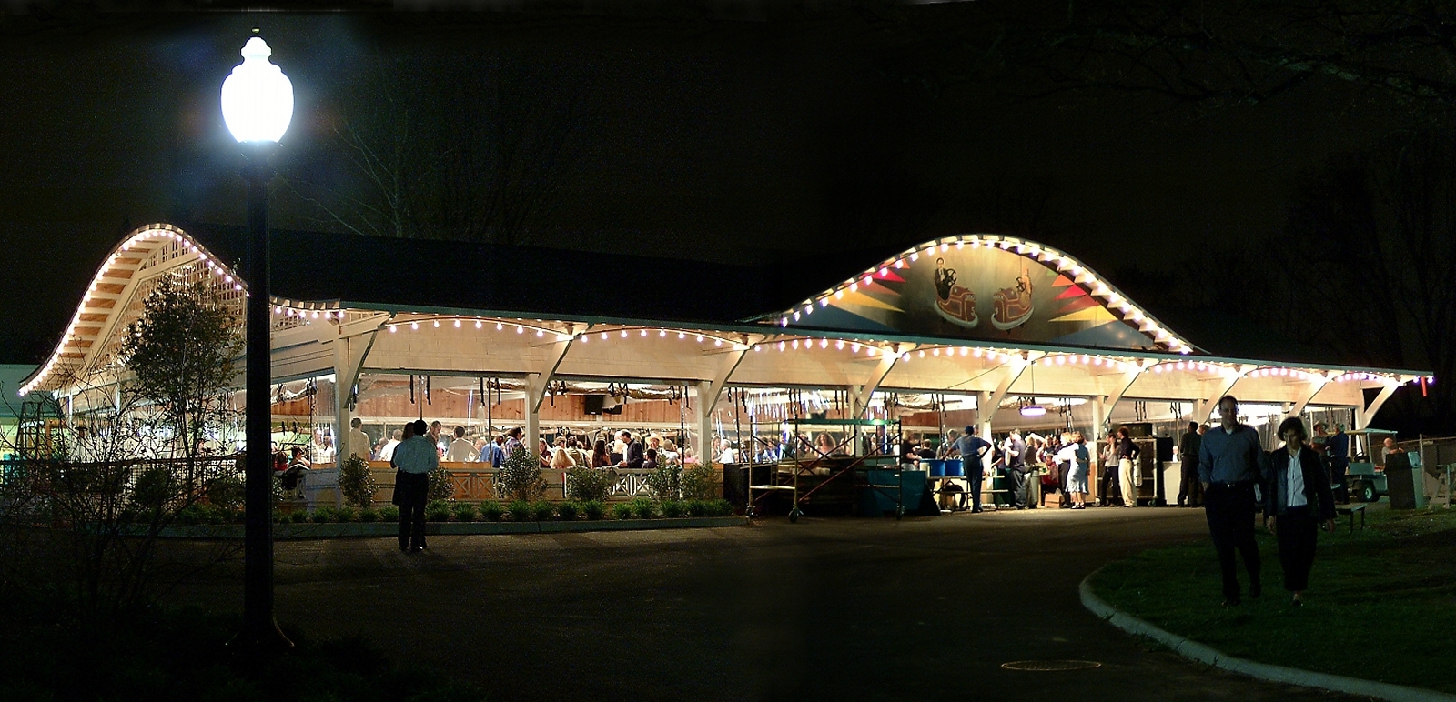 outdoor scene of open dance pavilion illuminated and evening dance crowd inside.