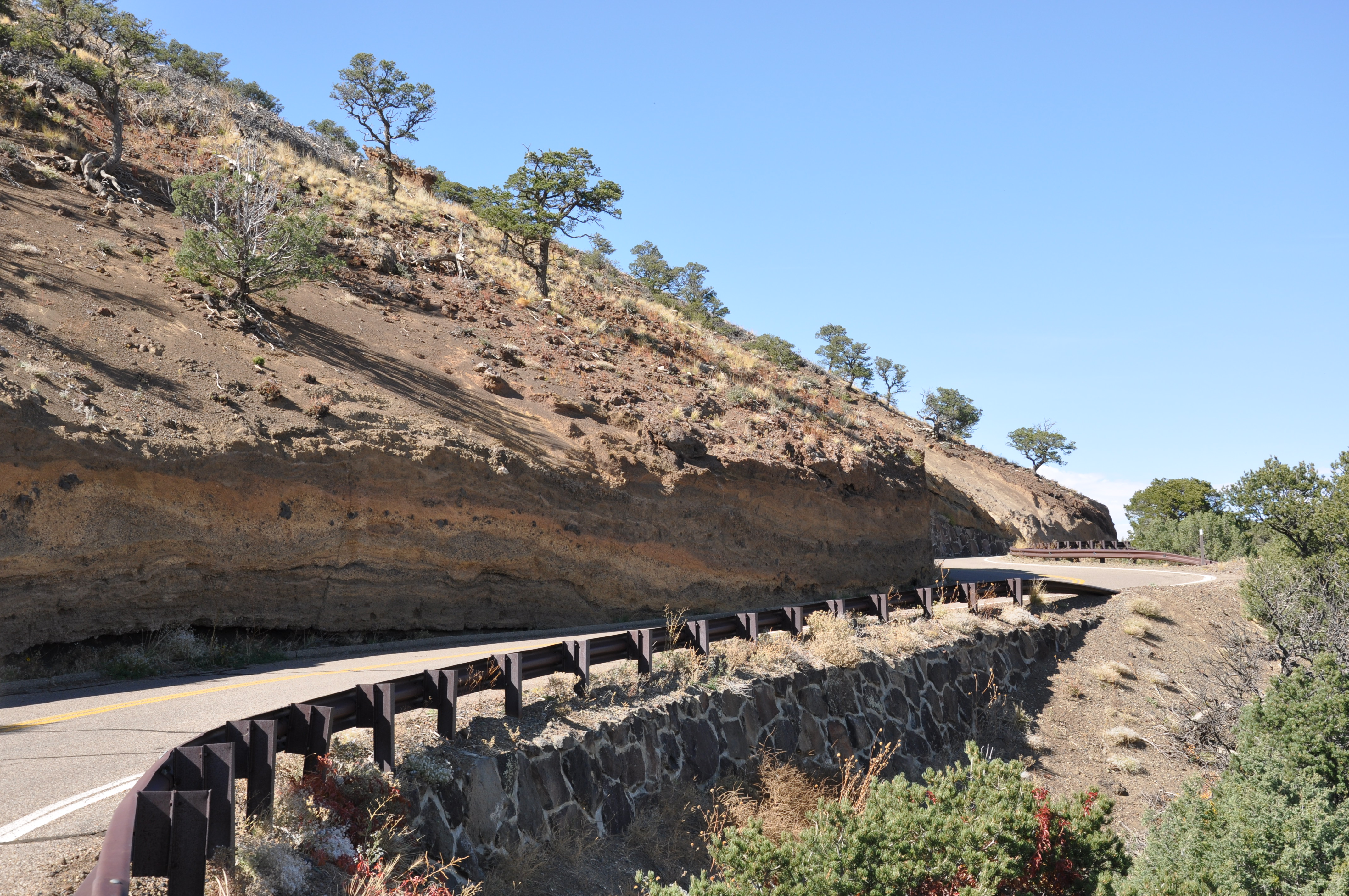 Layers of rock are visible in the steep hillside along a road.