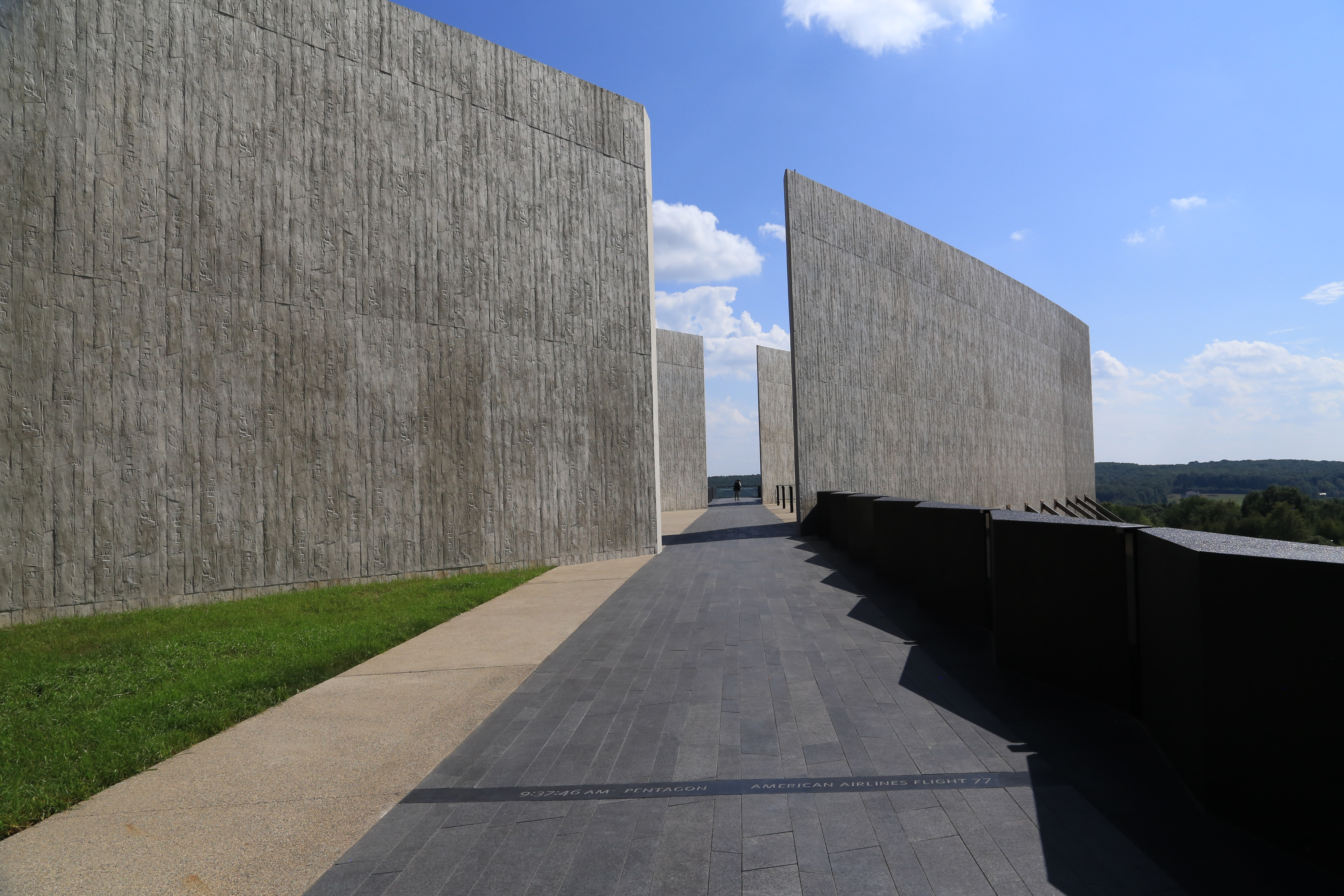 Tall gray walls with a gap and black pathway leading to the gap