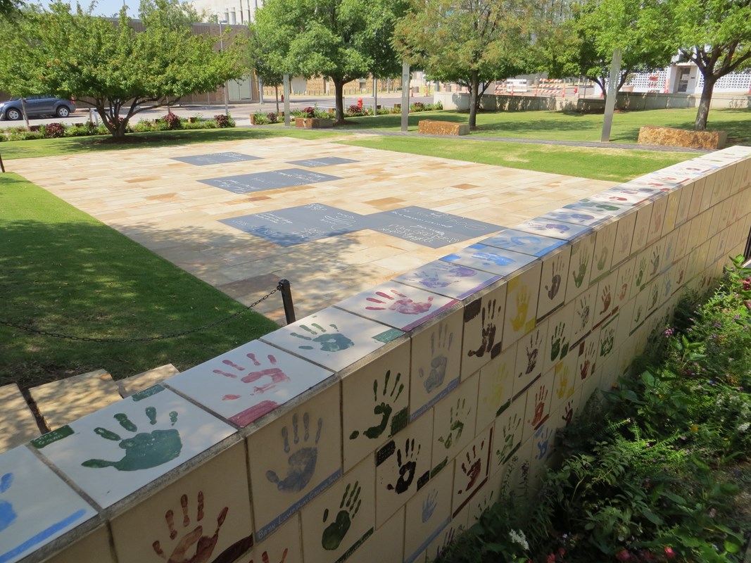 Tiles with hand prints and chalkboards set into the ground for children. 